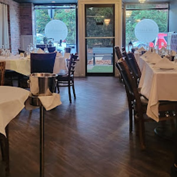 Cork & Crust Italian Kitchen dining room with set tables, dark wood floors, and large windows.