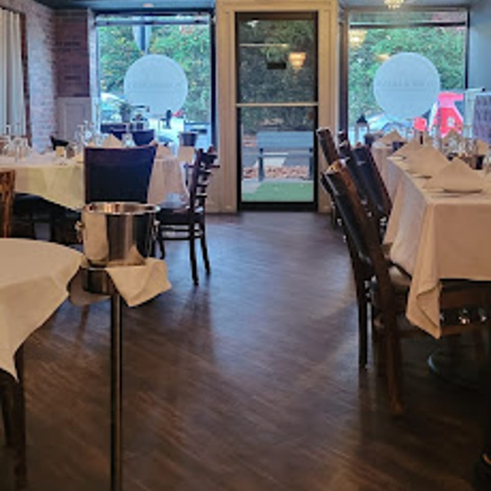 Cork & Crust Italian Kitchen dining room with set tables, dark wood floors, and large windows.