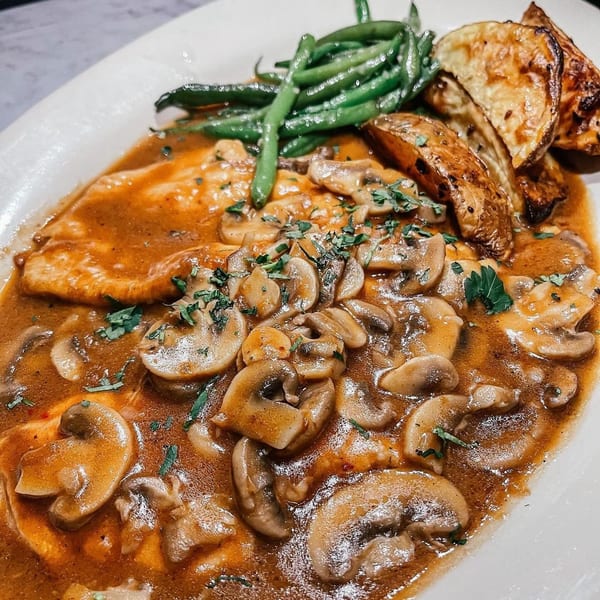Chicken Marsala with mushrooms, green beans, and roasted potatoes on a white plate.